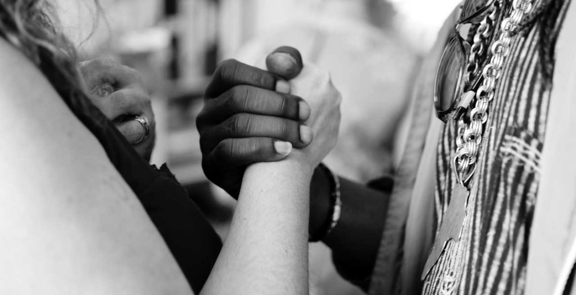 Image of two people shaking hands, one person is black and the other is white