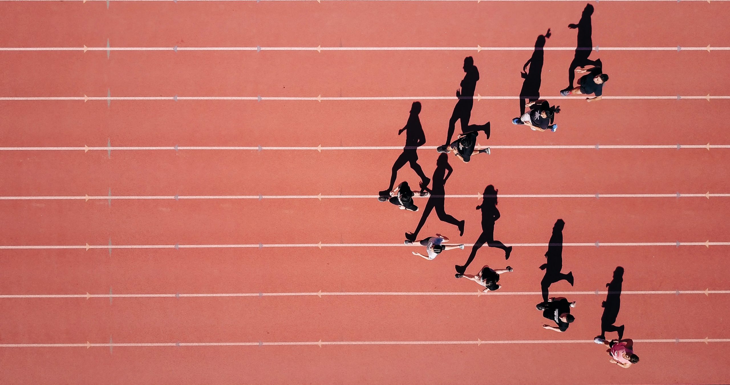Runners on a race track, with their shadows above them showing their silhouettes
