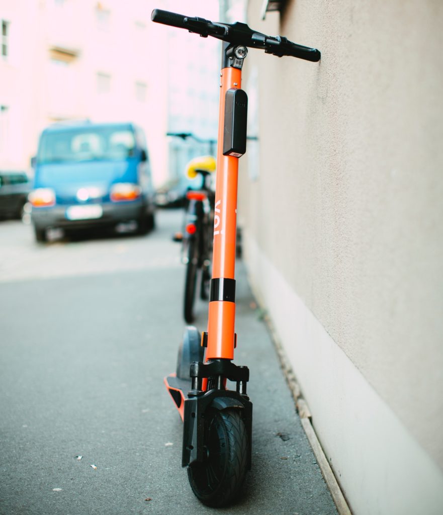 An e-scooter parked next to a wall on a pavement