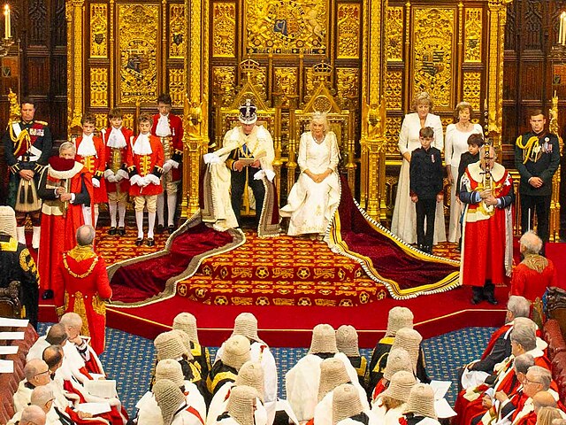 King Charles III and Queen Camilla sit on thrones to formally open the new session of the Houses of Parliament. 
