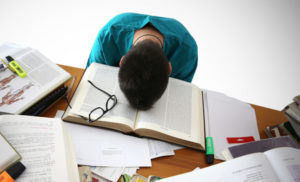 Boy studying with his head resting on a book in distress