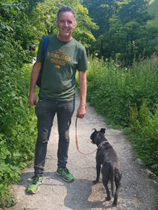 Chris Boshell with his dog, on a gravel pathway amongst lush green vegetation