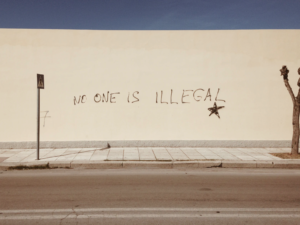 A wall with writing "no one is illegal"