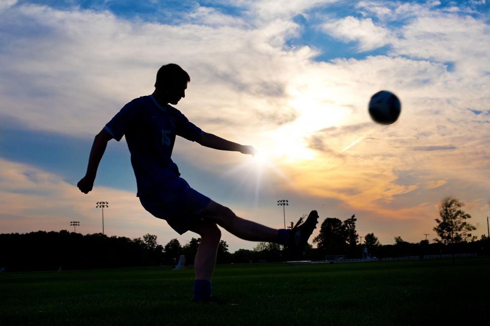 Boy playing football in the sunset