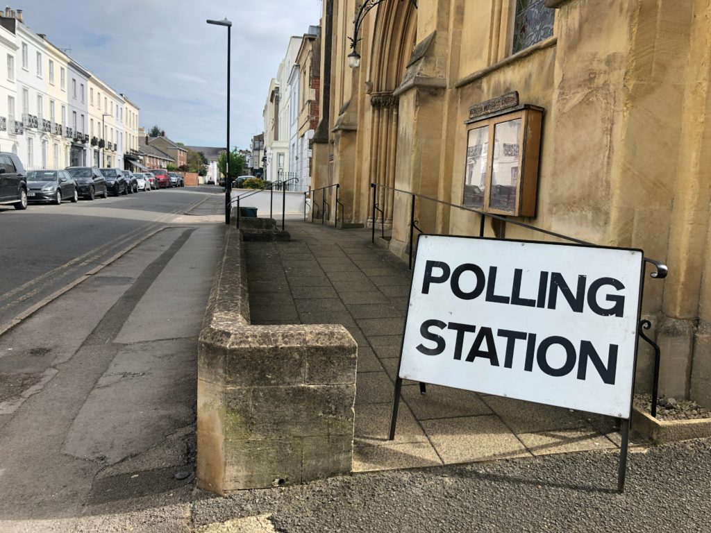 A polling station sign in front of a building. 