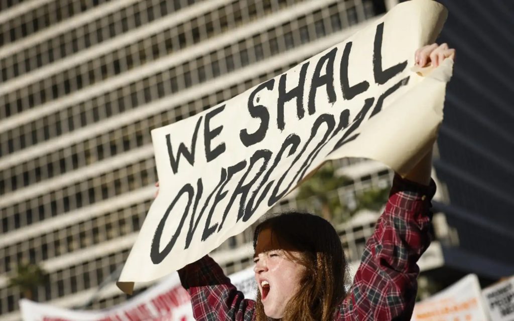 A woman holding a sign that reads "We Shall Overcome"
