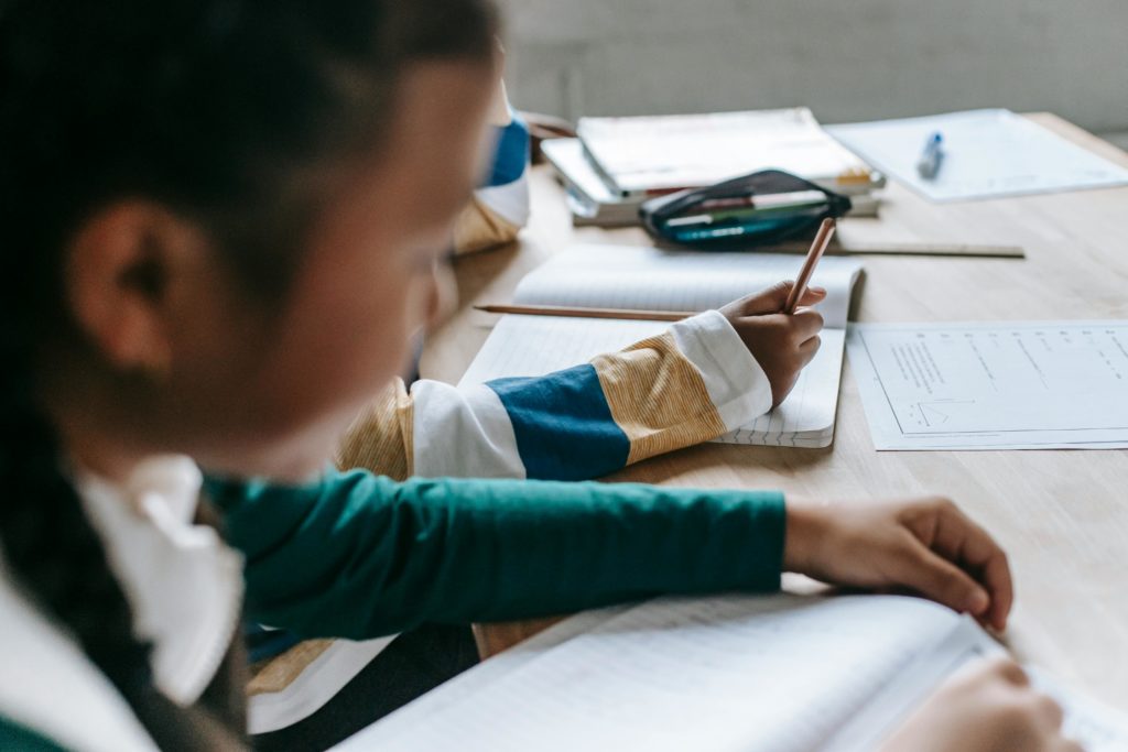 Child with hand over notebook in classroom setting