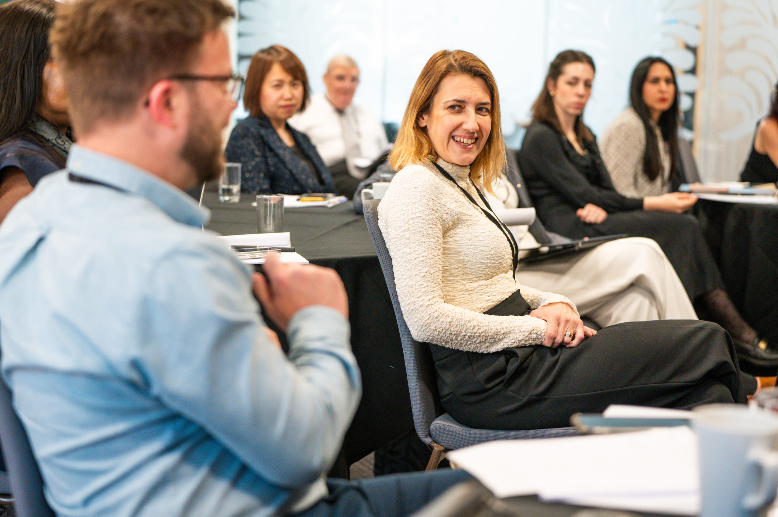 Conference attendees sitting in rows looking at an individual as he speaks.