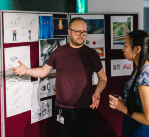 A photograph of IMSR researcher Jonathan Mueller talking to members of the public about his research on sulfation pathways and steroids at an engagement event