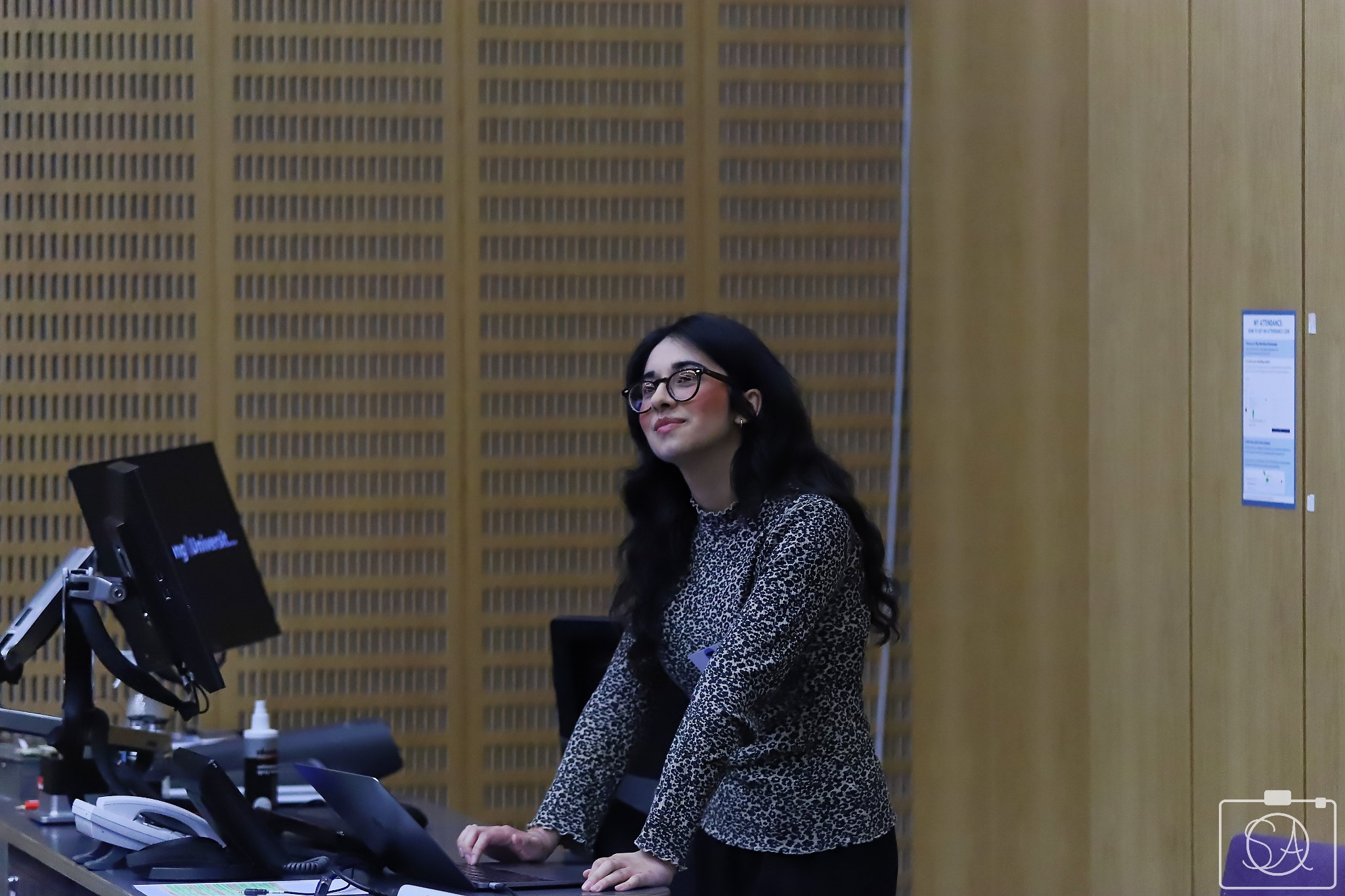 Hibah standing at a podium giving a talk