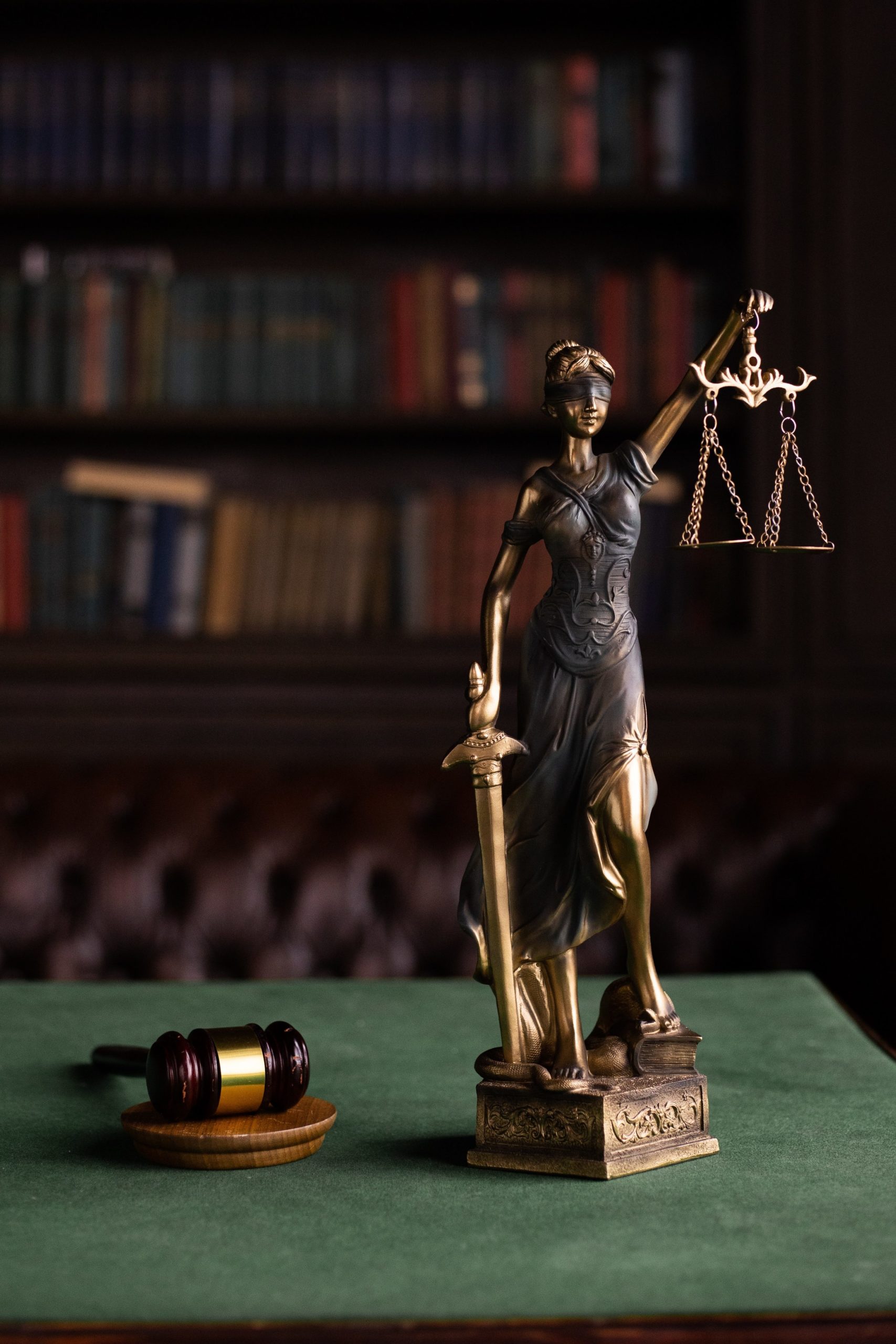 Photo of desk with gavel and lady justice sculpture holding the scales of justice