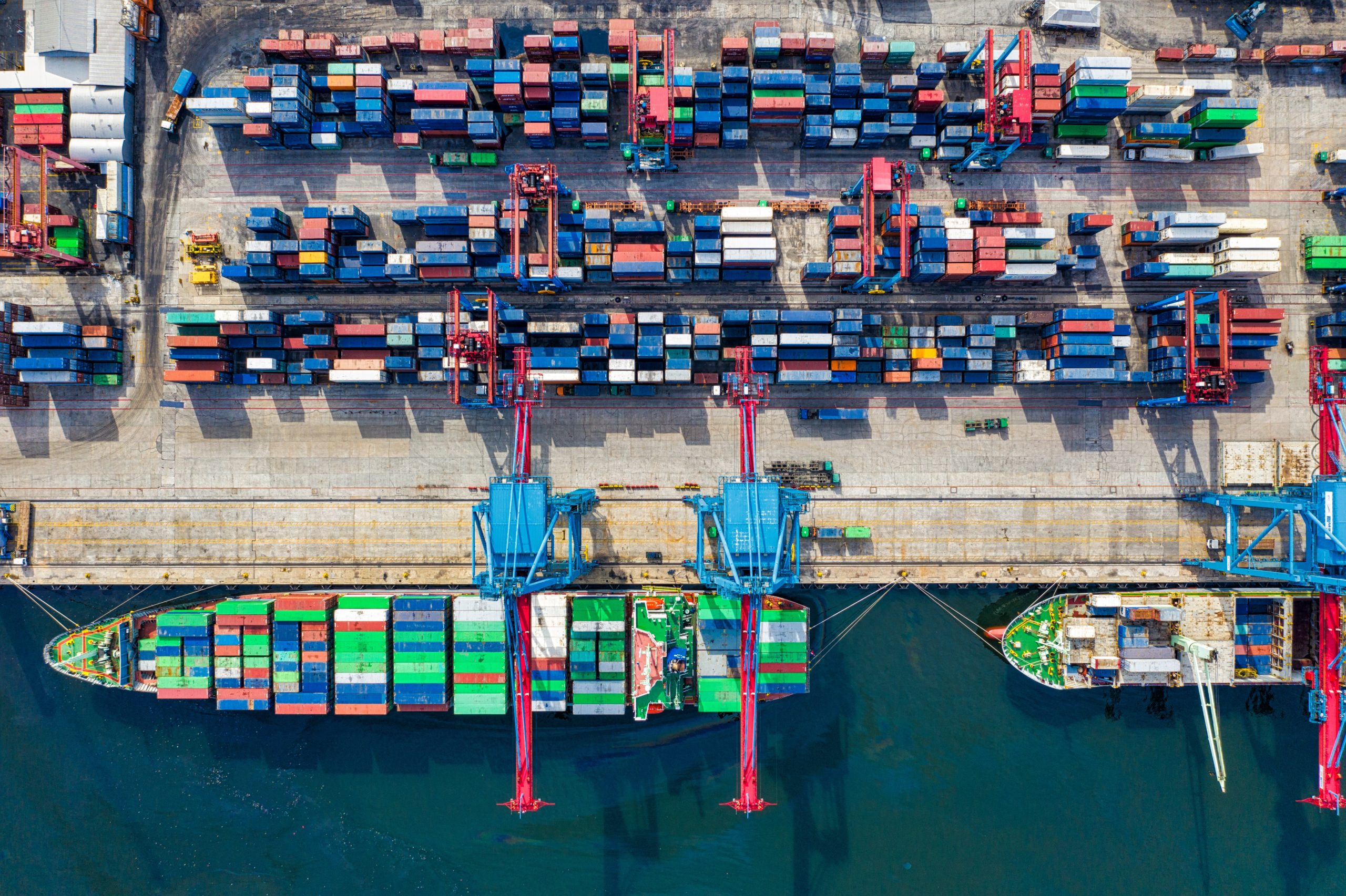 Cover photo of dock full of shipping containers and a cargo ship