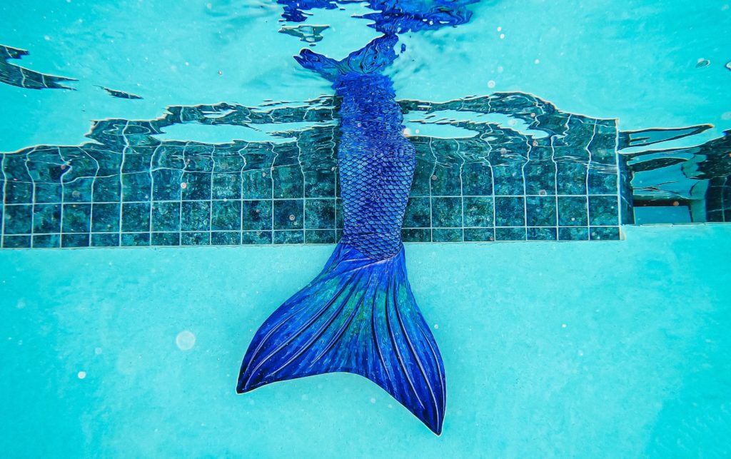 Underwater photograph of a mermaid tail entering a swimming pool