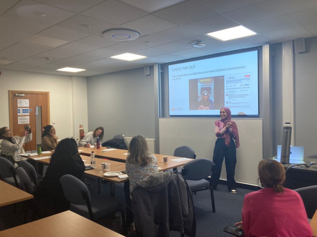The image shows a woman giving a presentation to a group of other people. The purpose of the image is to show some of the training that took place in the event.